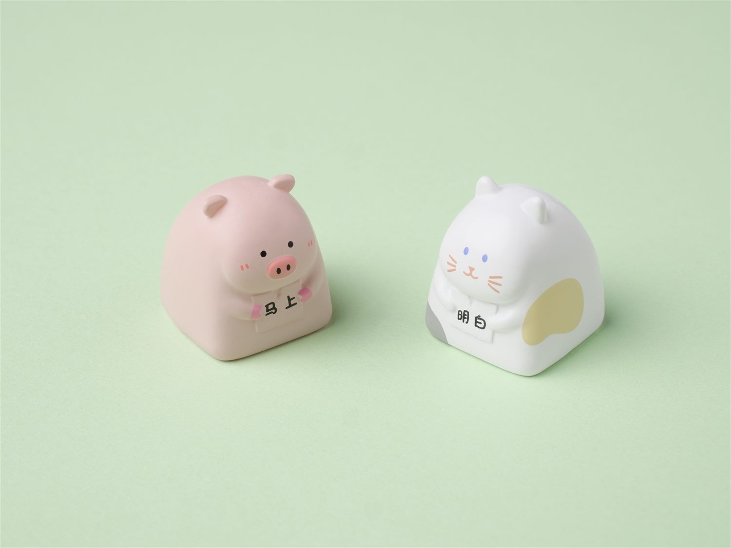 Pig and cat character artisan keycaps on a green background
